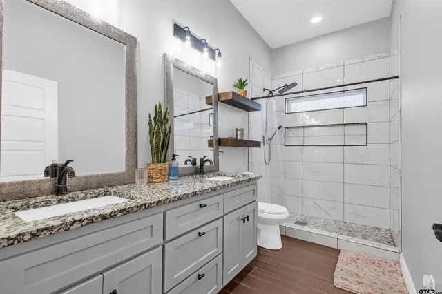a bathroom with a granite countertop sink a toilet and a mirror