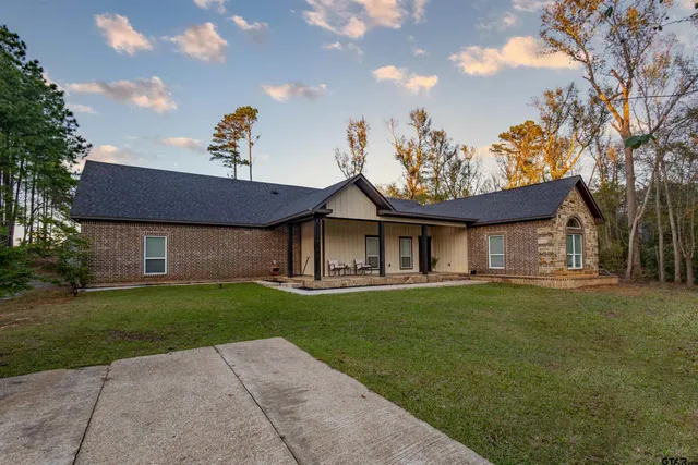 a view of a house with a big yard plants and large trees