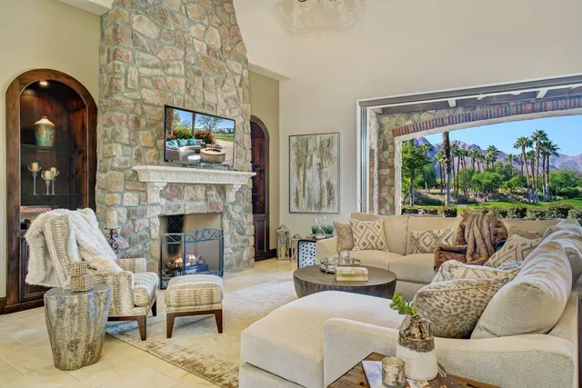 a living room with furniture a fireplace and a floor to ceiling window