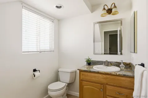 a bathroom with a granite countertop sink toilet and a mirror