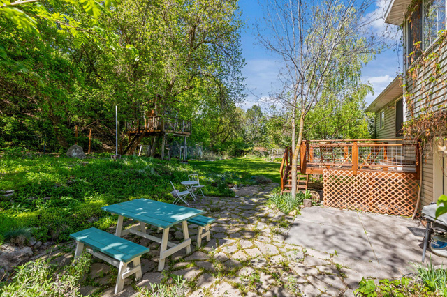 814 Mountain Road Logan, UT 84321 - Photo 40 of 42 Expansive backyard featuring a stone paver patio, a wooden deck with lattice skirting, and a multi-level treehouse structure