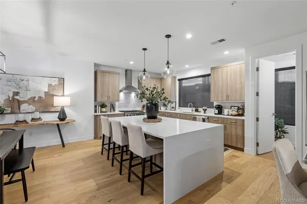 a kitchen with kitchen island a dining table chairs stainless steel appliances and cabinets