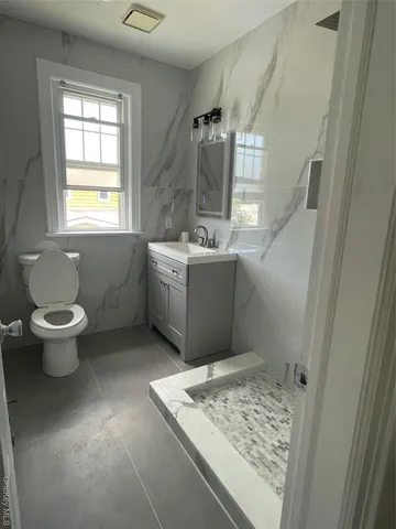 a bathroom with a granite countertop sink toilet and shower