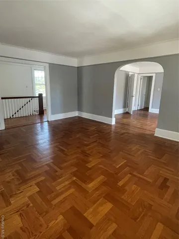 a view of an empty room with window and wooden floor