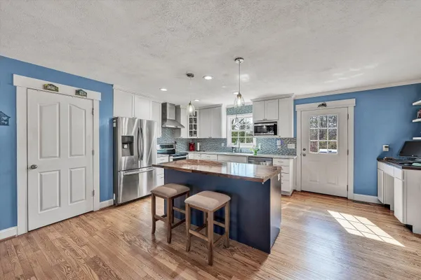 a large kitchen with stainless steel appliances kitchen island granite countertop a refrigerator stove microwave and sink