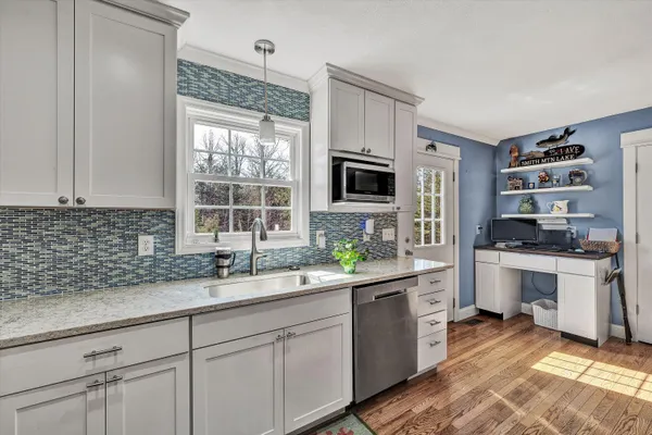 a kitchen with granite countertop stainless steel appliances and wooden floor