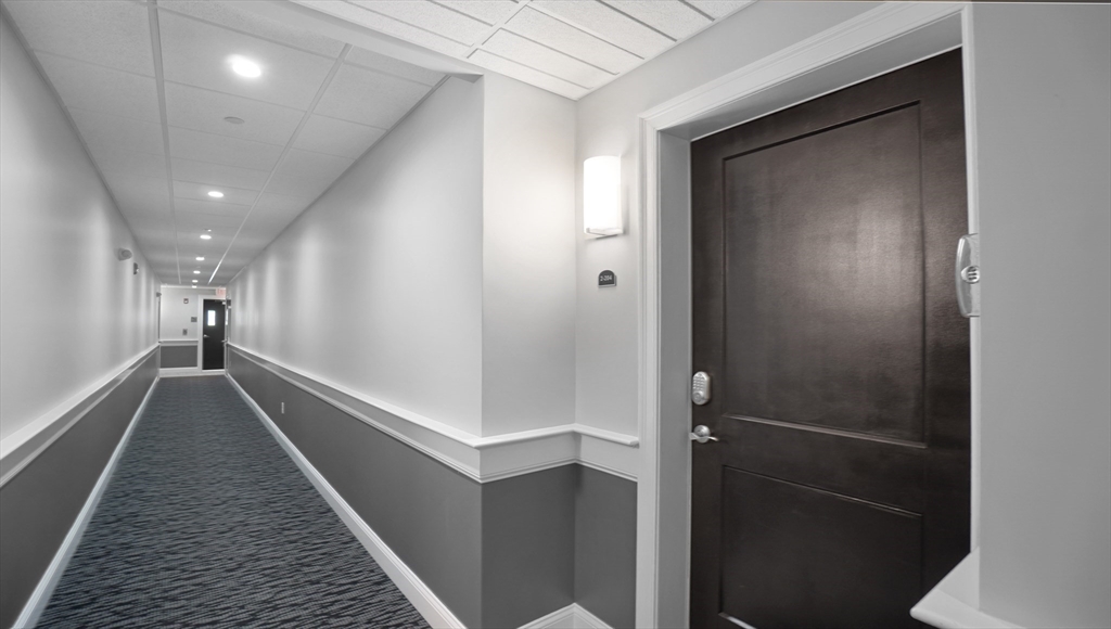 635 Old Post Road, Unit 204 Sharon, MA 02067 - Photo 15 of 22 a hallway with wooden floor and staircase