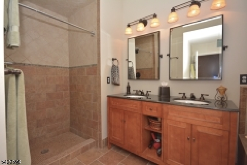 105 Well Sweep Road, Unit 105 Whitehouse Station, NJ 08889 - Photo 11 of 22 a bathroom with a granite countertop sink a mirror and a shower
