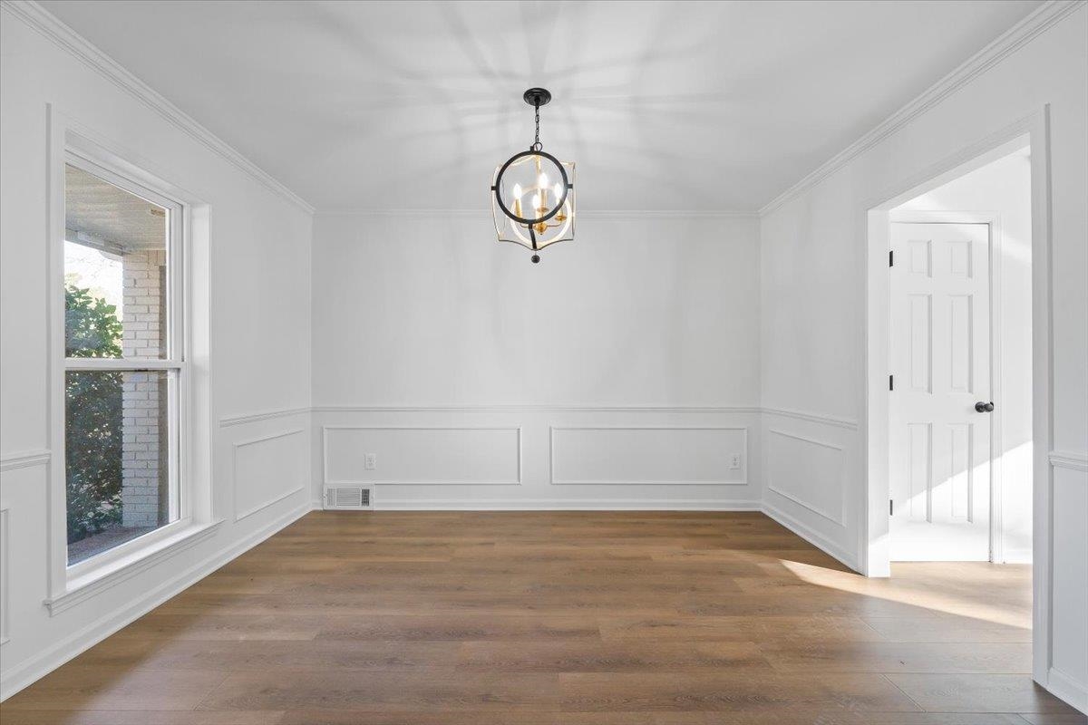 1676 Miller Farms Road Germantown, TN 38138 - Photo 7 of 37 Spacious room featuring wood-finish flooring, wainscoting, crown molding, and a contemporary chandelier