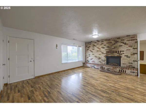 a view of empty room with wooden floor and fireplace