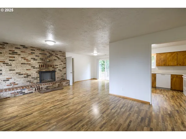 a view of a livingroom with wooden floor and a fireplace