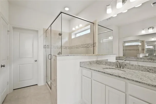 a bathroom with a granite countertop sink a mirror and a shower