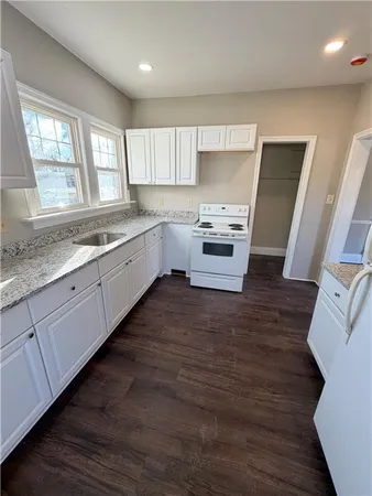 a large kitchen with granite countertop a large window a sink and stainless steel appliances