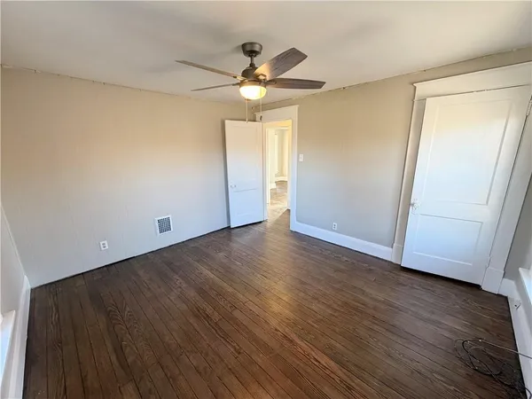 an empty room with wooden floor fan and window