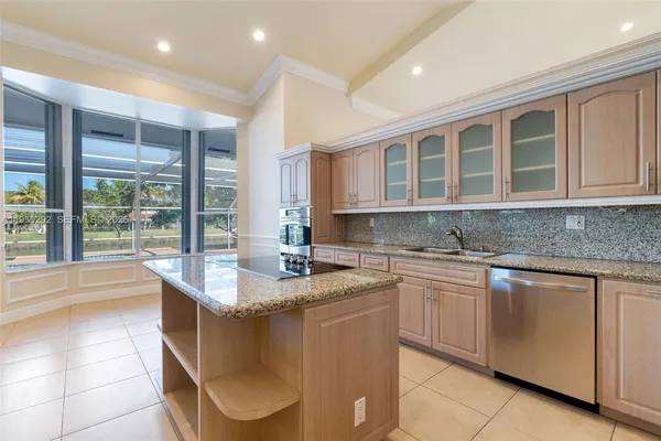 a kitchen with kitchen island granite countertop a sink and white cabinets