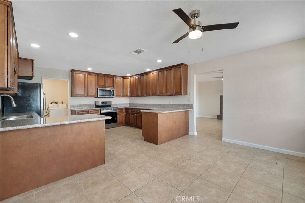 9846 Sunny Vista Road Phelan, CA 92371 - Photo 11 of 34 a kitchen with stainless steel appliances granite countertop a stove top oven a sink a refrigerator and a granite counter top