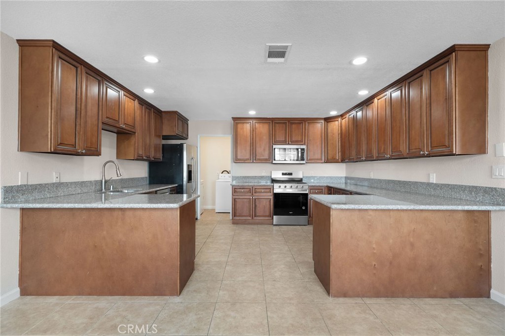 9846 Sunny Vista Road Phelan, CA 92371 - Photo 12 of 34 a kitchen with stainless steel appliances granite countertop wooden cabinets a stove a sink and a oven