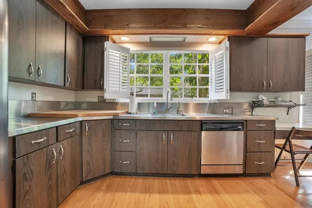 a kitchen with stainless steel appliances granite countertop wooden cabinets a sink and dishwasher with wooden floor
