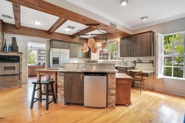 a kitchen with stainless steel appliances granite countertop a stove top oven a sink a dining table and chairs with wooden floor