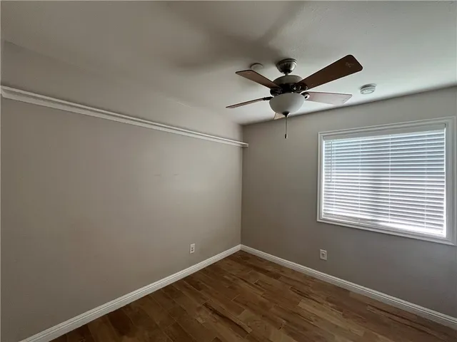 a view of an empty room with a window and a ceiling fan