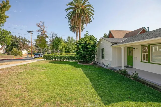 a palm tree sitting in front of a house with a big yard