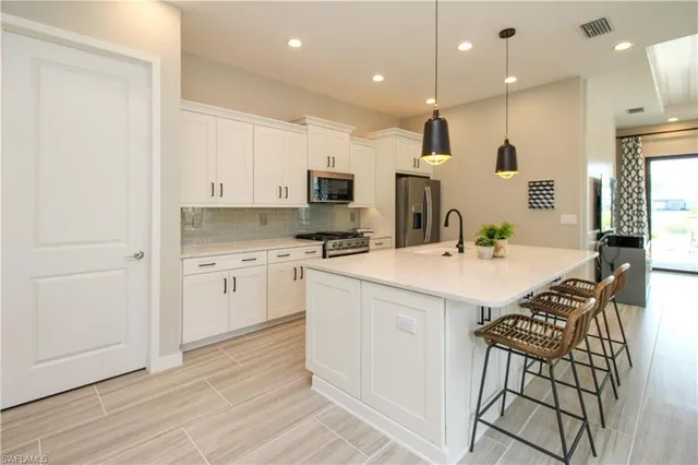 a kitchen that has a lot of white cabinets and stainless steel appliances