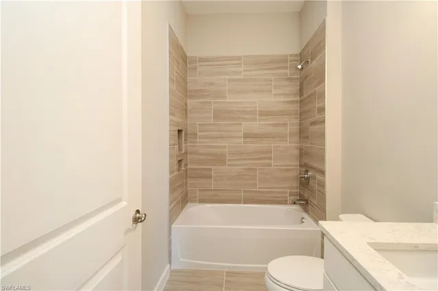 a bathroom with a granite countertop bathtub shower sink vanity and toilet