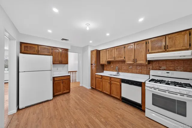 a kitchen with stainless steel appliances granite countertop a refrigerator a stove top oven a sink and dishwasher with wooden floor