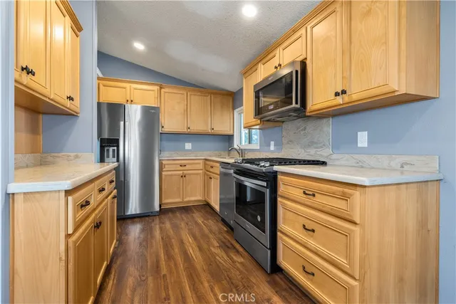 a kitchen with granite countertop wooden floors stainless steel appliances and window