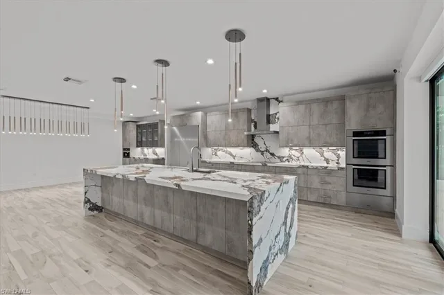 a kitchen with stainless steel appliances granite countertop a sink a stove and a wooden floors