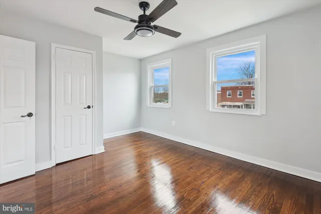 an empty room with wooden floor and ceiling fan