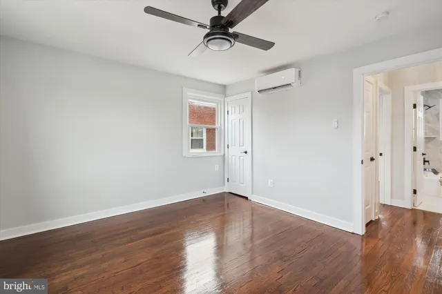 an empty room with wooden floor a ceiling fan and windows