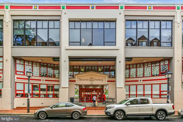 a front view of a building with lots of trees and flowers around