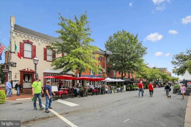 a view of a cafe with a couple of people seating in front of retail shops