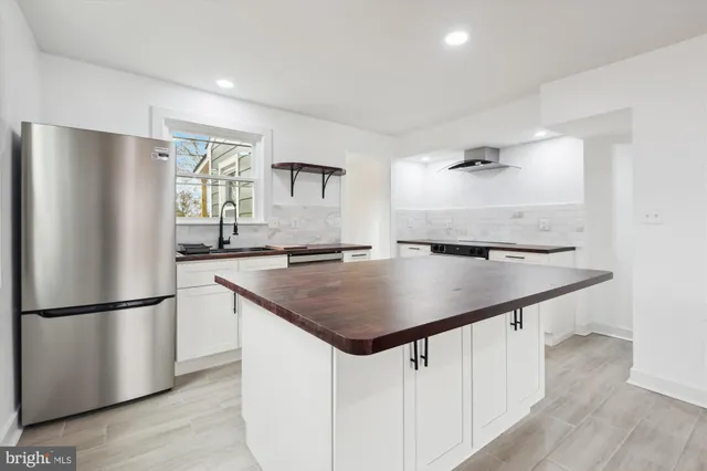 a kitchen with kitchen island white cabinets a refrigerator and a window