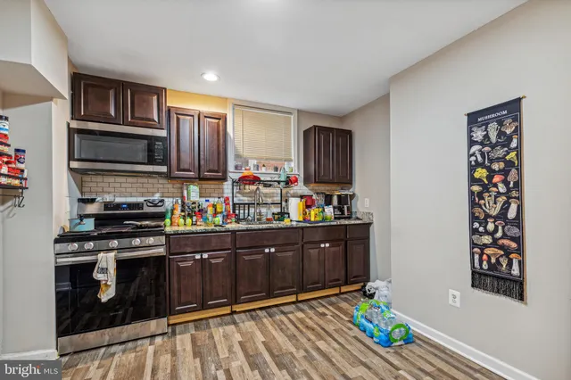 a kitchen with stainless steel appliances kitchen island granite countertop a refrigerator stove and wooden floor