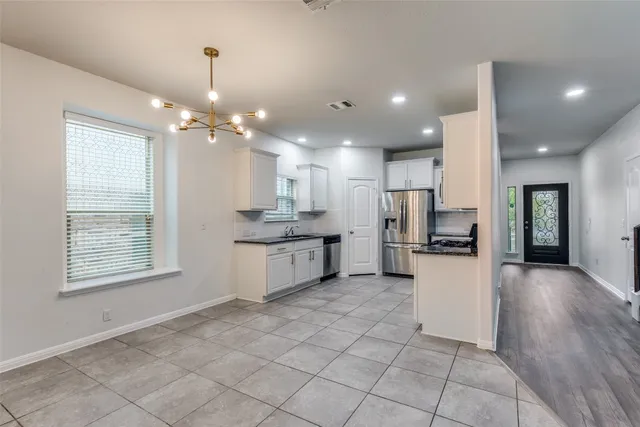 a large white kitchen with kitchen island a stove a sink cabinets and a dining table