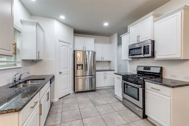 a kitchen with stainless steel appliances granite countertop a stove a sink and a refrigerator