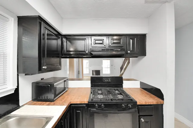 a kitchen with stainless steel appliances granite countertop a refrigerator a sink a stove and a refrigerator