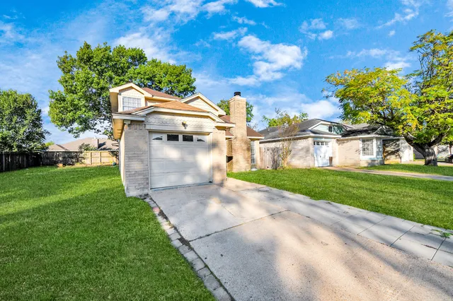 a view of a white house next to a yard with big trees