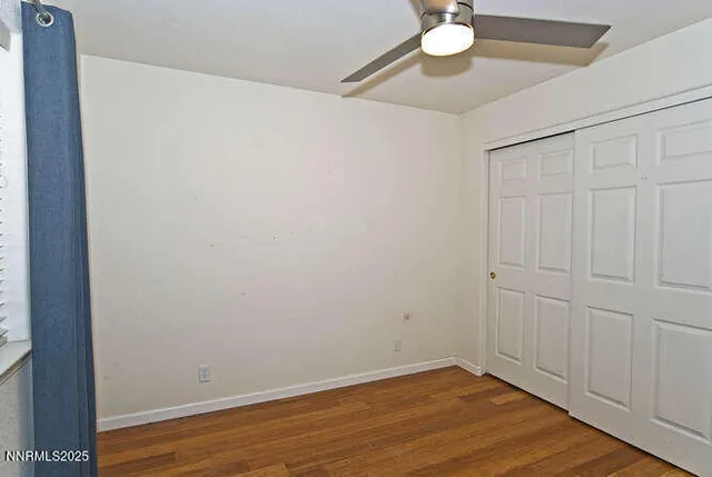 a view of an empty room with wooden floor and a chandelier
