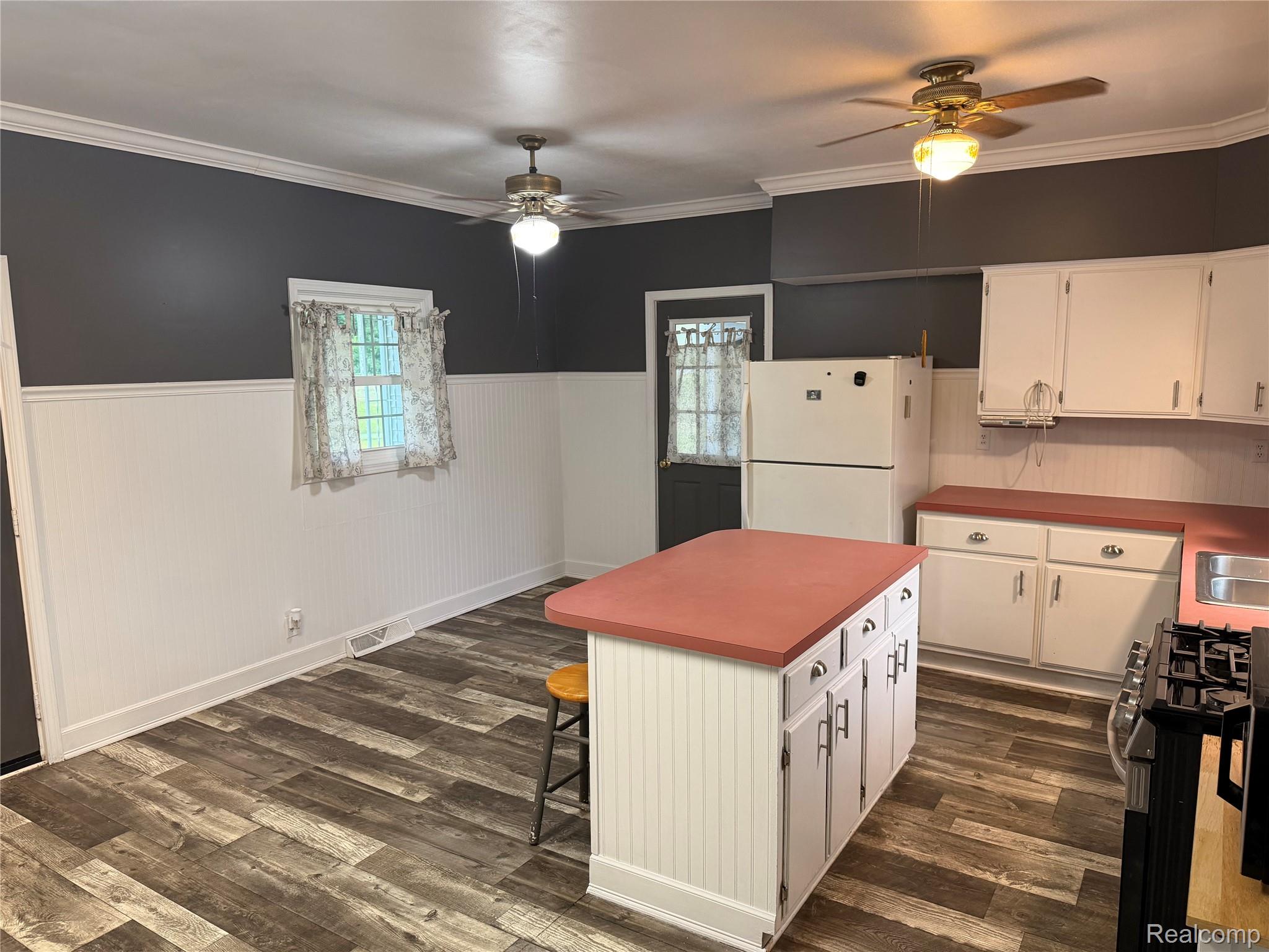 2402 Mertz Road Caro, MI 48723 - Photo 8 of 26 White cabinetry with red countertops, wood-finish flooring, white beadboard wainscoting, and ceiling fans