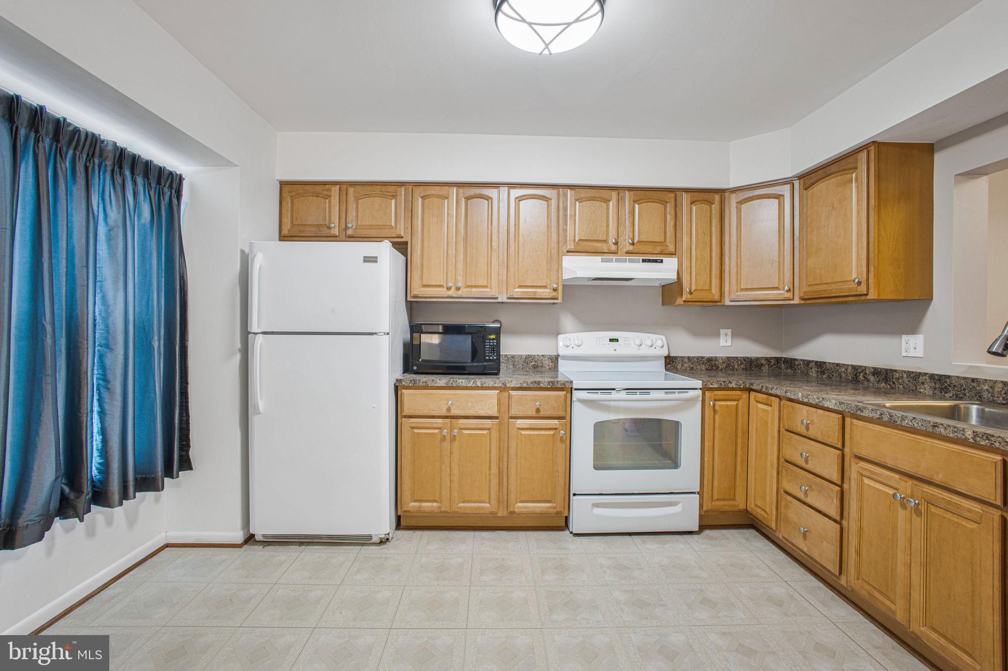 2830 Schoolhouse Circle Silver Spring, MD 20902 - Photo 13 of 58 a kitchen with a refrigerator sink stove and cabinets