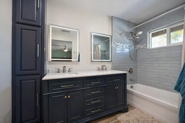 a bathroom with a tub a double vanity sink and mirror