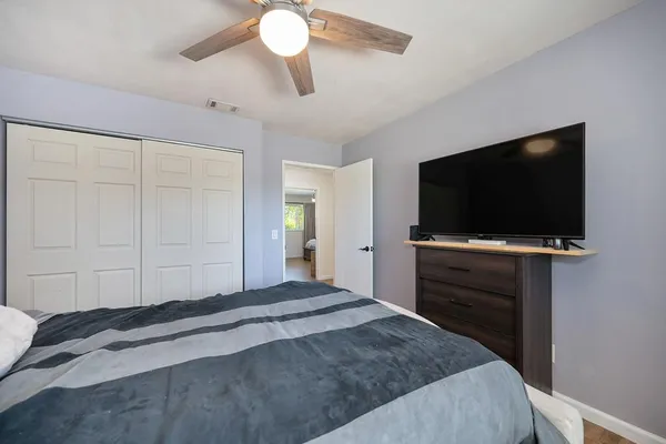 a bedroom with a bed and a flat tv screen on wall