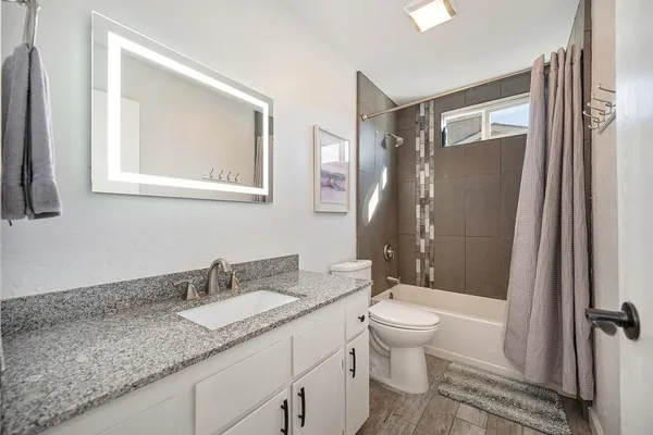 a bathroom with a granite countertop sink toilet and shower