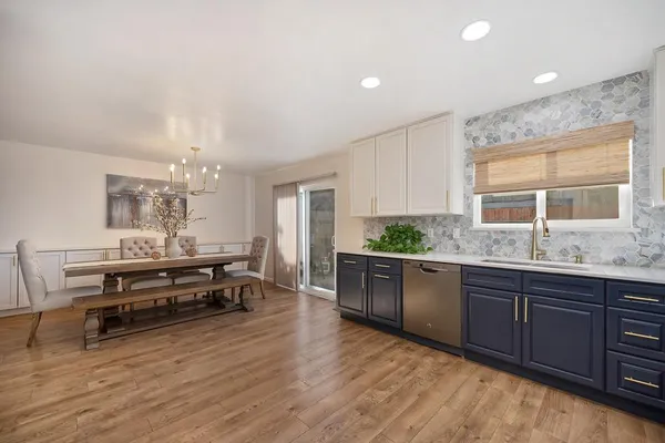 a large white kitchen with wooden floor and stainless steel appliances