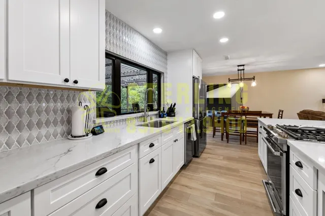 a kitchen with stainless steel appliances a sink a stove a table and chairs