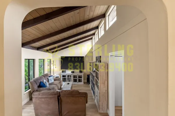 a living room with furniture a flat screen tv and floor to ceiling window