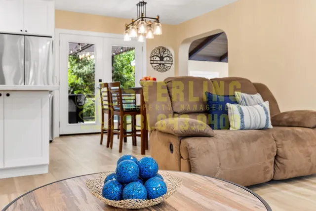 a living room with furniture kitchen view and a large window